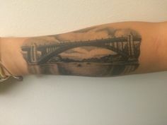 a man's arm with a bridge tattoo on it