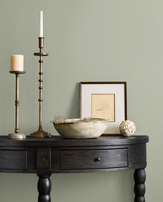 a wooden table with a bowl and two candles on it next to a framed photograph