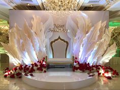 a white chair sitting on top of a table next to a chandelier filled with red and white flowers