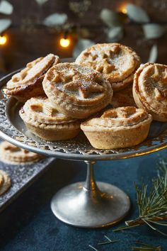 A metal cake stand with a pile of golden mince pies with star shapes on their lids