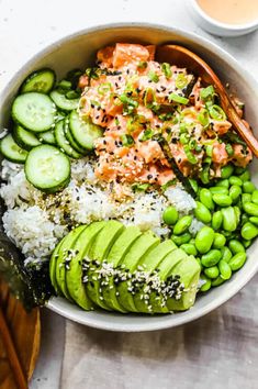 a bowl filled with rice, cucumbers and salmon