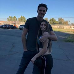 a man and woman are standing together in the parking lot with their arms around each other