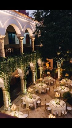 an outdoor dining area with tables, chairs and candles lit up in front of the building