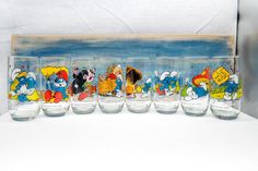 a row of glasses with cartoon characters painted on the glass and in front of them