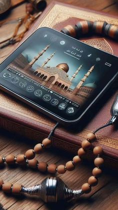 an electronic device is sitting on top of a book with rosary beads and a watch