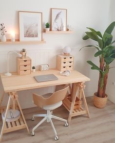 a wooden desk topped with a laptop computer next to a potted plant