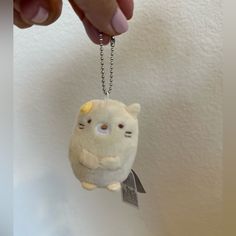 a person is holding a small stuffed animal keychain with a cat on it