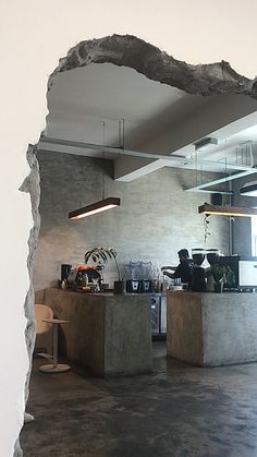 a hole in the wall shows an open kitchen and dining area with tables, chairs, and plants