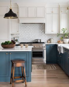 a kitchen with blue and white cabinets, an island countertop and wooden stools