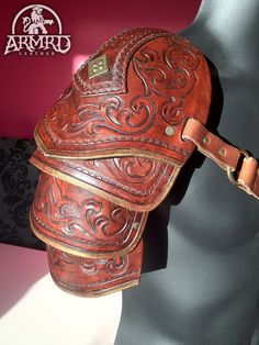 a brown leather hat with intricate designs on it's back and shoulder strap is displayed in front of a mannequin head