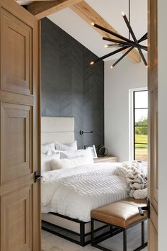 a large white bed sitting in a bedroom next to a wooden ceiling mounted light fixture