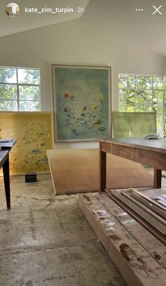 an empty room with several pieces of wood on the floor and paintings in the background