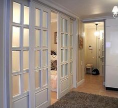 an open door leading to a bedroom with a bed in the background and a rug on the floor