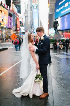 a bride and groom standing in the middle of a city street on a rainy day