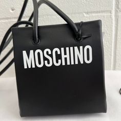 We Do Not Trade, Users Making Low-Ball Offers Will Be Ignored & Blocked Only One Is Available! Wear It As A Shoulder Bag Or As A Bucket Bag! Moschino Couture Black Leather Mini Shopper / Shoulder Bag With White Logo Msrp $790 Ss21 Collection By Jeremy Scott Rare And Highly Sought After Collector's Item Sold Out Everywhere And Impossible To Get! Super Rare And Super Cute! 100% Authentic!!! Condition: Brand New With Tags, Moschino Dust Bag Included Color: White/Black Pattern: Logo Material: Leathe Black Shopping Bags With Logo Hardware, Trendy Logo Shoulder Bag For Evening, Chic Evening Bags With Logo Strap, Evening Bags With Logo Strap, Trendy Black Shoulder Bag With Logo, Rectangular Shoulder Bag With Logo Strap For Shopping, Luxury Bags With Logo Tag For Everyday Use, Modern Everyday Bags With Logo Tag, Chic Black Shoulder Bag With Logo