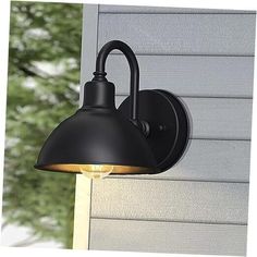 a black outdoor light on the side of a house with trees in the back ground