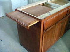 a wooden desk with an open drawer in the middle and two doors on each side