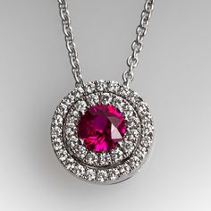 This gorgeous ruby pendant necklace is centered with one (1), prong set, round cut natural ruby and bordered with a double halo setting accented with thirty-nine (39), prong set, round brilliant cut diamonds. The pendant measures 9.8mm in diameter and 5.3mm thick. The pendant is suspended from an eighteen karat white gold cable link style neck chain measuring 16-1/2 inches in length. Signed Spark. Luxury Ruby Jewelry With Pave Setting, White Gold Necklaces With Round Center Stone, Round White Gold Necklace With Center Stone, Fine Jewelry Round Pendant Necklace With Center Stone, Exquisite Round Ruby Necklaces, Classic Necklace With Round Pendant Center Stone, White Gold Ruby Necklaces With Brilliant Cut, White Gold Ruby Necklace With Brilliant Cut, Classic Round Pendant Necklace With Center Stone