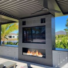 an outdoor living area with a fireplace and television