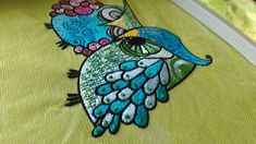 a close up of an embroidered bird on a green surface