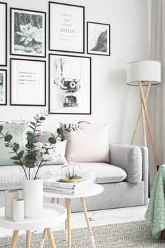 a living room filled with white furniture and pictures on the wall above it's coffee table