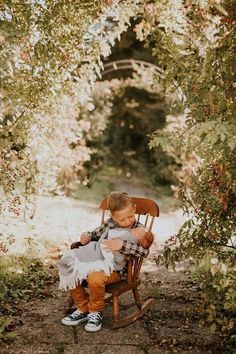 a little boy sitting in a wooden rocking chair