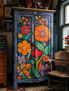 an ornate painted armoire with flowers on it in a room next to a window