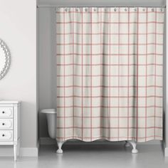 a bathroom with a shower curtain, mirror and white dresser in front of the window