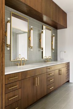 a bathroom with two sinks, mirrors and wooden cabinetry on the wall above them