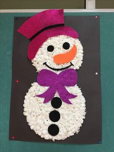 a snowman made out of rice sitting on top of a black board with a purple hat and bow tie