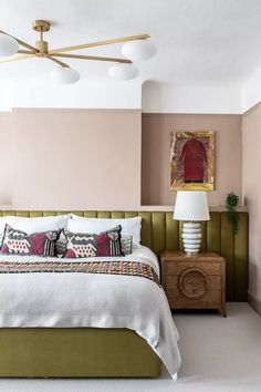 a bedroom with pink walls and green headboard, white bedding, and two nightstands