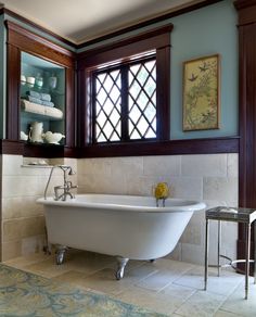 a bath tub sitting under two windows in a bathroom