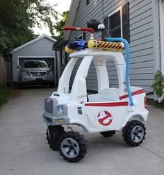 a white and red toy car parked in front of a house with a fireman's helmet on top