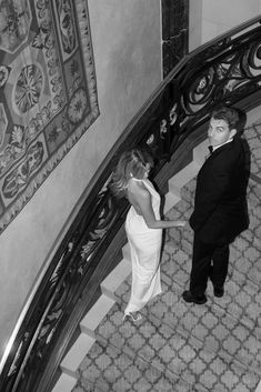 black and white photograph of two people standing on the stairs looking up at each other