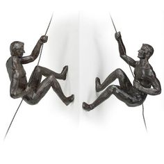 two sculptures of men hanging on ropes, one holding the other's hand and another sitting down