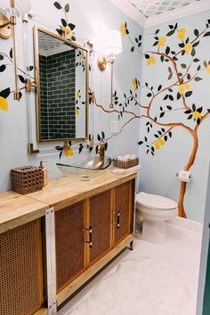 a bathroom decorated in blue and yellow with a tree painted on the wall next to the toilet