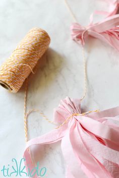 two rolls of twine on a table with pink and yellow ribbons