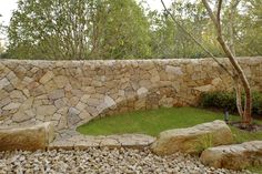 a stone wall with grass and rocks around it