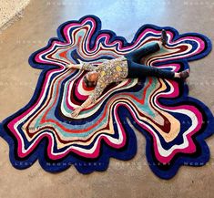 a woman laying on top of a multicolored rug in the middle of a room