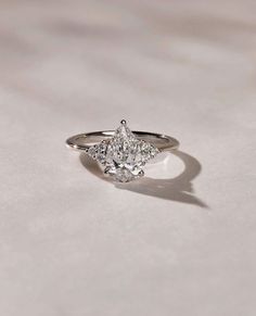 a three stone diamond ring on top of a white surface with light shining in the background