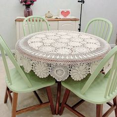 the table is set with four chairs and a doily covered tablecloth on it