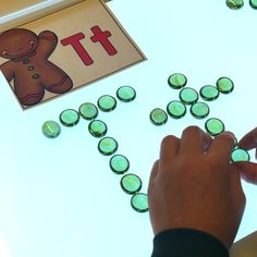 a child is playing with green buttons on a white surface next to a gingerbread cutout