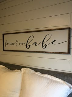 a bed with two pillows and a framed sign above it