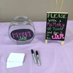 a table topped with a glass vase filled with writing next to a chalkboard sign