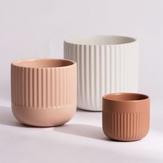 three vases sitting next to each other on a white surface with no one in them