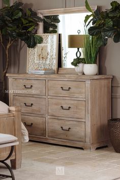 a bedroom scene with focus on the dresser and mirror, potted plant and chair