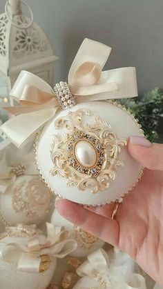 a hand holding an ornament with pearls and bows