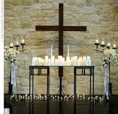 a table with candles and flowers in front of a cross