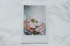 a polaroid with flowers in it sitting on a marble surface