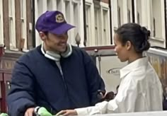 a man and woman standing next to each other in front of a white truck on the street